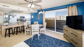 A modern kitchen with white cabinets, a microwave, and a dining area with a blue patterned rug. - PI 501: Flip Flop Flats - Spectacular East 5th Floor Corner Unit Memory Maker (Fort Walton Beach)