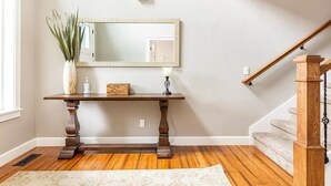 Una escalera con barandales y pasamanos de madera que conduce a un rellano con una consola de madera y un espejo.