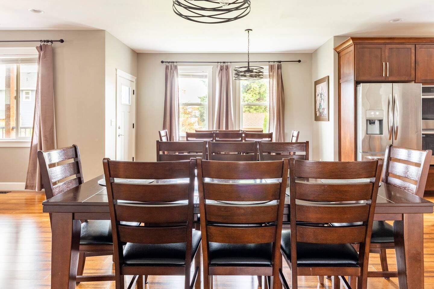 A dining area with a wooden table and chairs, a chandelier, and a kitchen with wooden cabinets and appliances.
