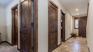 A hallway with wooden doors, a stone floor, and a small bench. - Luxury Cabin with Private Hot Tub! Close to Village! (Mammoth Lakes)