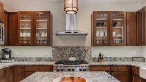 A kitchen with wooden cabinets, a gas stove, and a marble countertop. - Luxury Cabin with Private Hot Tub! Close to Village! (Mammoth Lakes)