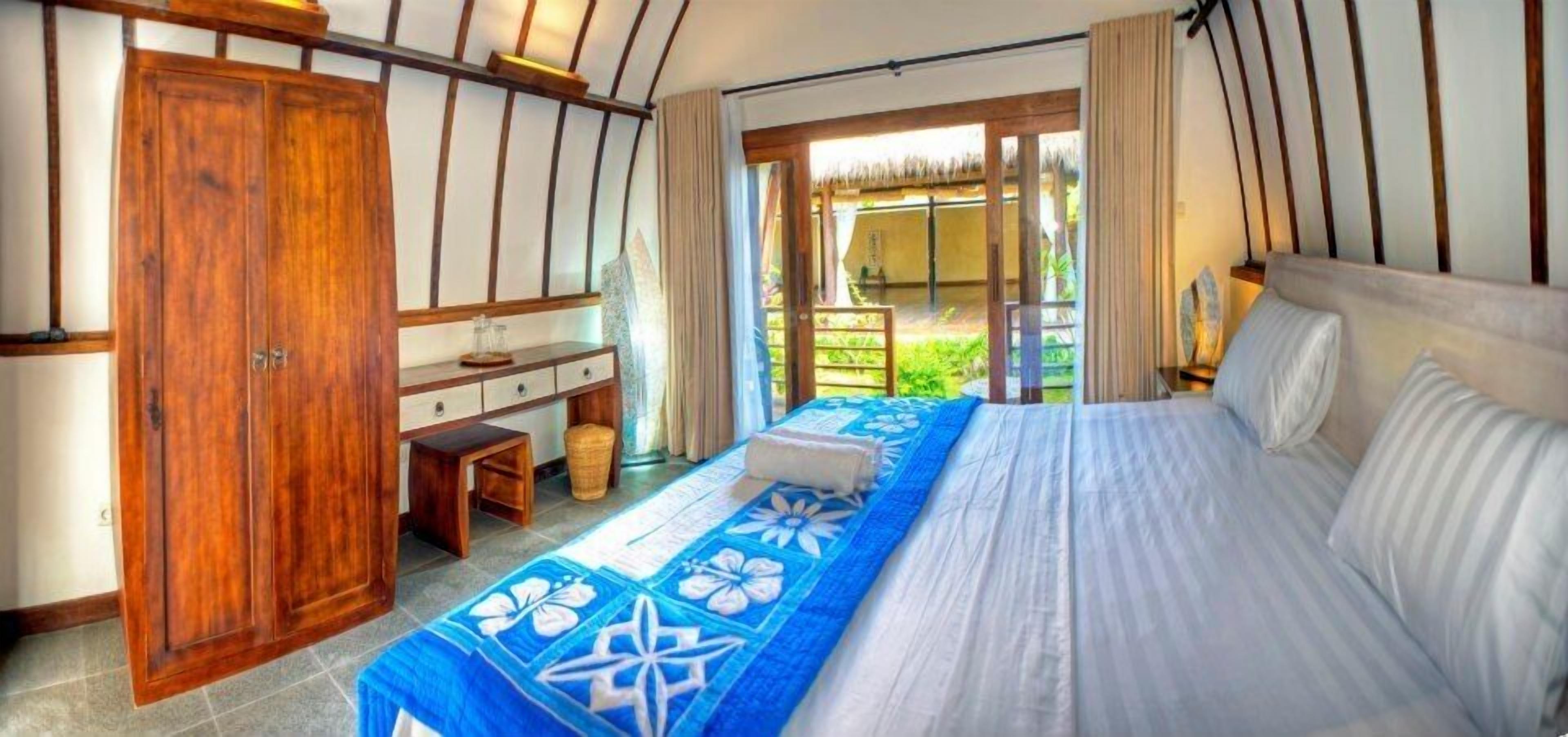 A bedroom with a bed, a desk, and a wardrobe.