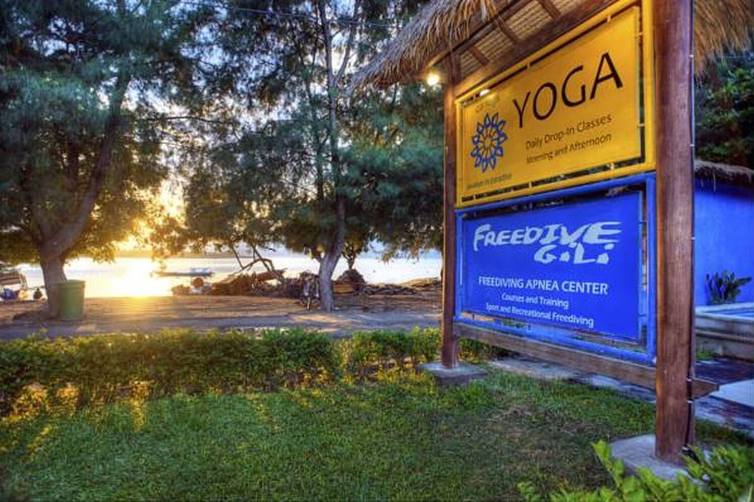 Señalización para un centro de yoga y un centro de buceo profundo, con un atardecer de fondo.
