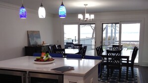A modern kitchen with a central island, dark wooden flooring, and pendant lighting. - Modern 300 ft lakefront with pool (Mayville)