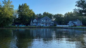 A lakeside property with a large house featuring a porch and a dock. - Modern 300 ft lakefront with pool (Mayville)