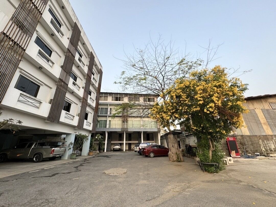 A multi-story building with a parking area in front.