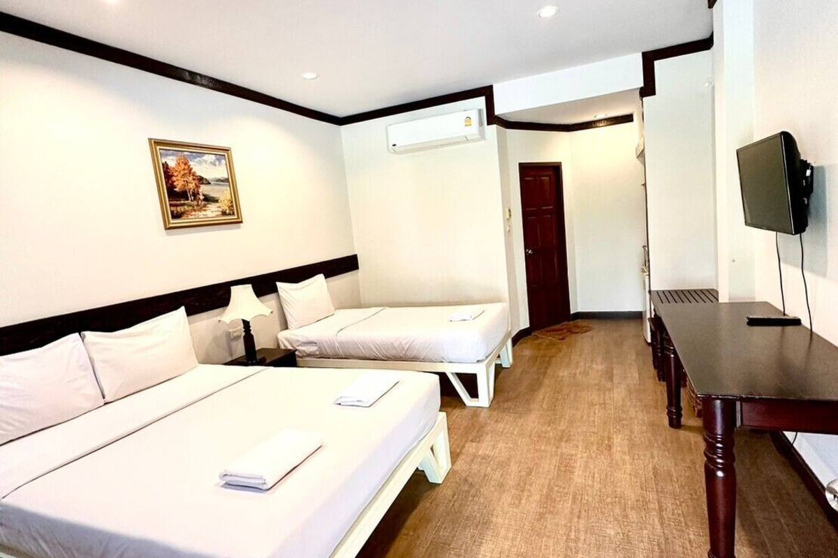 Quarto de hotel com duas camas de solteiro, uma escrivaninha, uma cadeira, uma televisão e um aparelho de ar condicionado.