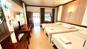 A hotel room with a wooden desk, two beds, a small table, and a view of the outdoors. - Bansuan Resort (Nakhon Sawan)