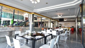 A spacious indoor dining area with multiple tables and chairs, a modern ceiling design, and a view of the outside through large windows. - Bansuan Resort (Nakhon Sawan)