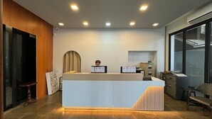 A reception desk with a modern design, a wooden accent wall, and a glass door leading to a balcony. - Bansuan Resort (Nakhon Sawan)