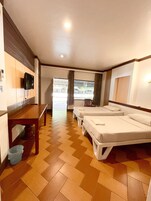 Una habitación de hotel con piso de madera, una cama, una mesita y un televisor instalado en la pared.