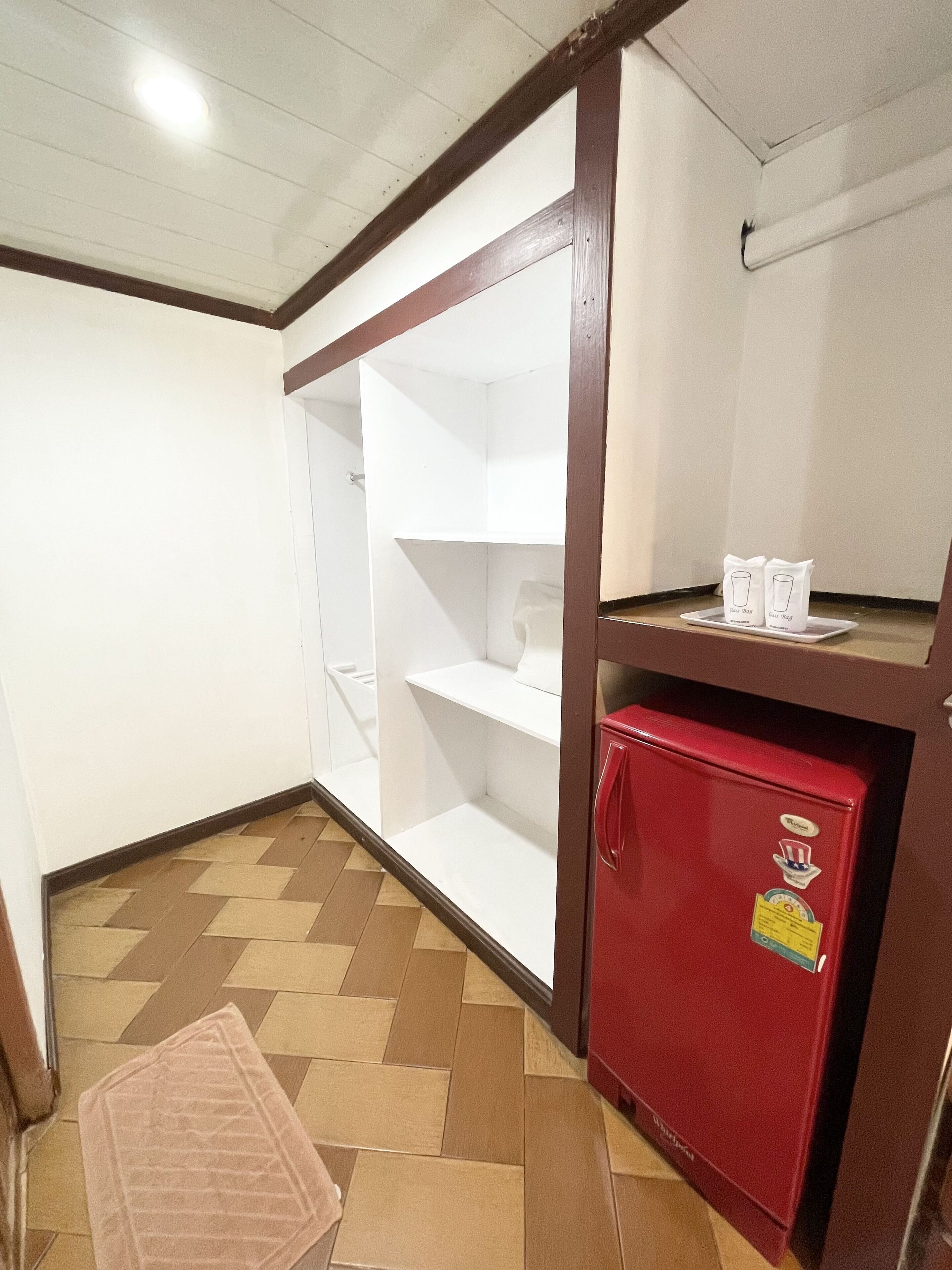 Eine kleine Küchenzeile mit einem roten Kühlschrank, einem Holzschrank und einem gefliesten Boden.