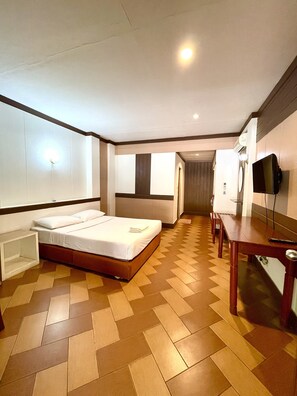 Ein Hotelzimmer mit Bett, Schreibtisch, Stuhl, Fernseher und Badezimmer.