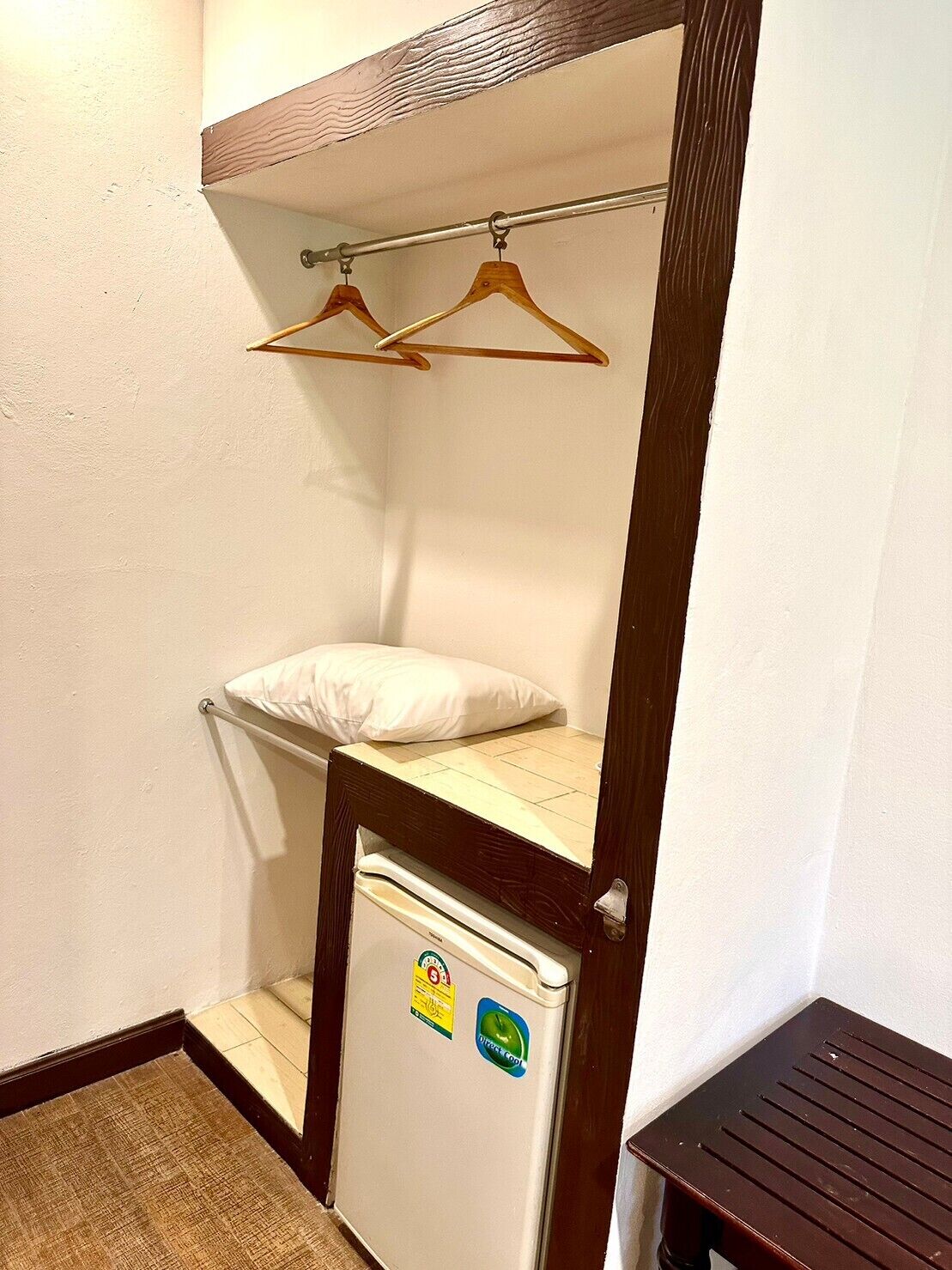 A compact room with a bunk bed, a small refrigerator, and a wooden table.