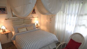 Une chambre à coucher avec un lit, une table de chevet, une chaise et une fenêtre avec des rideaux.