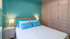 A bedroom with a bed, nightstands, a dresser, and a large wardrobe.