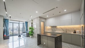 A modern kitchen with a marble countertop, a built-in oven, and a large window overlooking the city. - Wow! Homes by Christine - Vinhomes Luxury (Ho Chi Minh City)