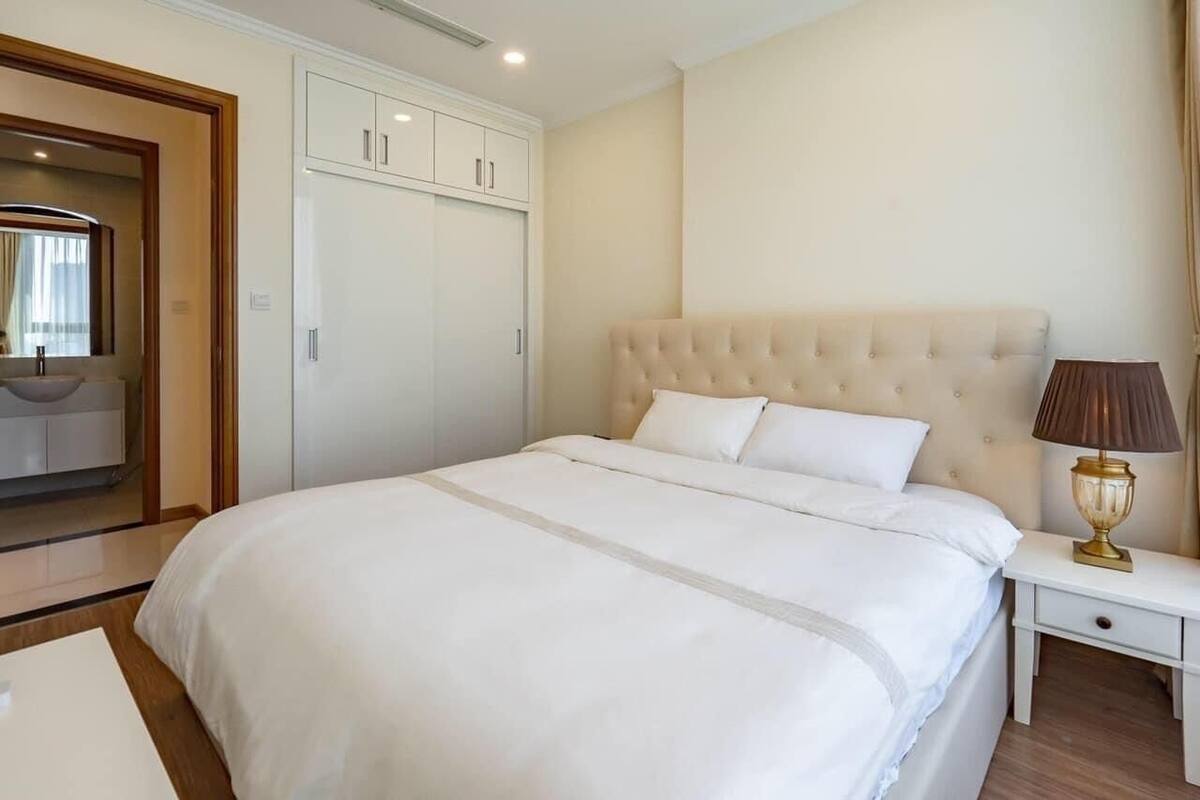 Ein Hotelzimmer mit einem großen Bett, einem Kleiderschrank, einem Nachttisch mit Lampe und einem Spiegel.