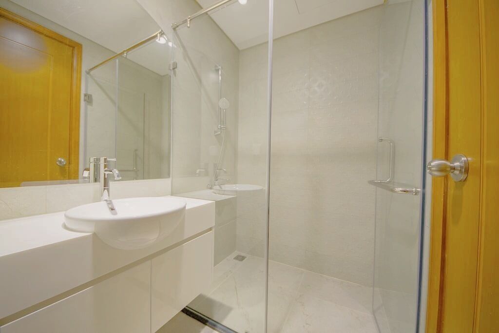 Un baño moderno con ducha de vidrio, tocador doble y un espejo grande.
