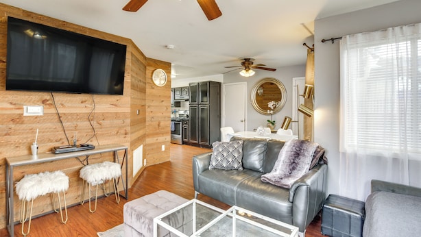 Un salon moderne avec un canapé en cuir, une table basse en verre et un mur décoratif en bois.