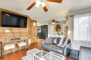 Ein modernes Wohnzimmer mit einer Ledersofa, einem Glastisch und einer Wand mit Holzpaneelen.