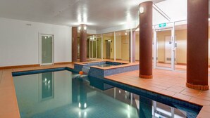 Une piscine intérieure à l’eau claire, dotée d’un sol carrelé et de quelques piliers.