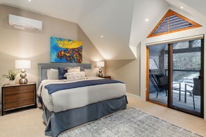 Une chambre avec un grand lit, un tableau, une lucarne et une porte-fenêtre coulissante donnant sur un balcon.