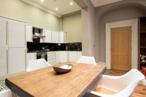 Una cocina moderna con armarios blancos, una mesa de comedor de madera y una silla blanca.