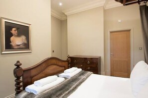 Una habitación de hotel con una cama de madera, un tocador, un cuadro en la pared y una puerta.