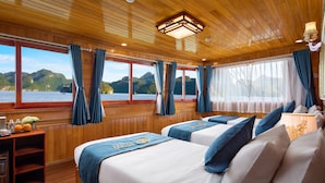 A cabin with two beds, wooden walls, and large windows offering a view of the water and hills. - La Paci Cruises (Hai Phong)