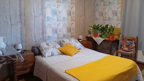 A bedroom with a bed, bedside tables, a chair, a desk, and a wall with patterned wallpaper. - STUDIO Appart gite Petite Halte,... work, vacation. (Wavrans sur l'aa)