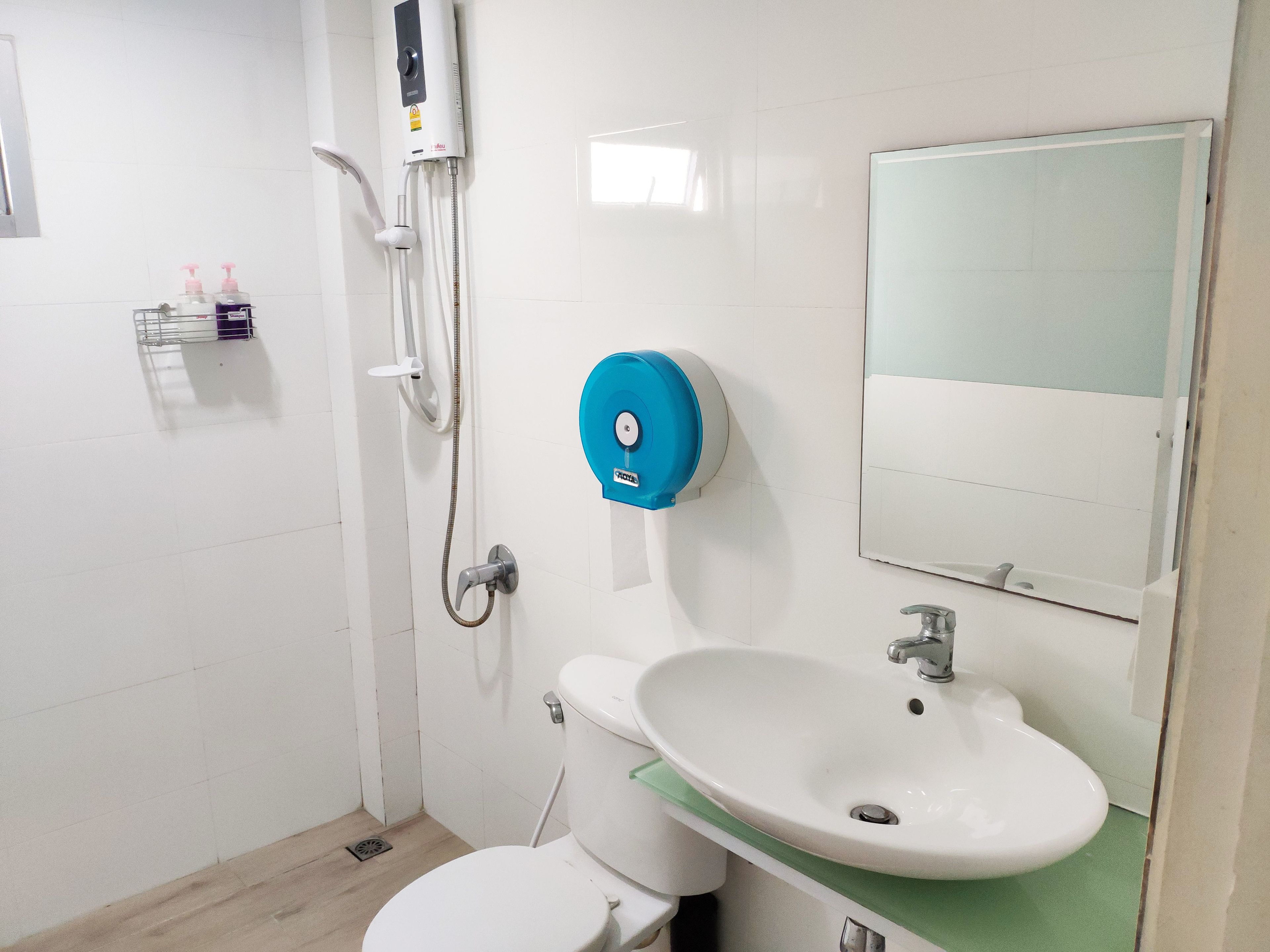 A small bathroom with a toilet, sink, and shower.