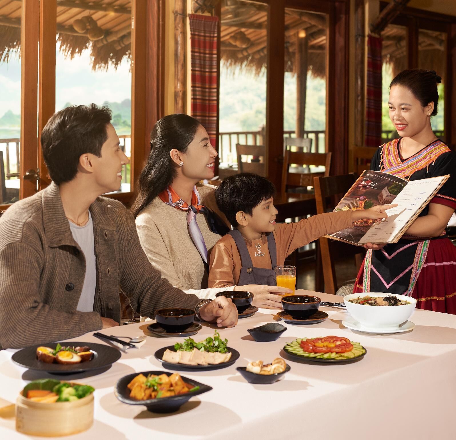 A family dining at a restaurant with a view of the outdoors.