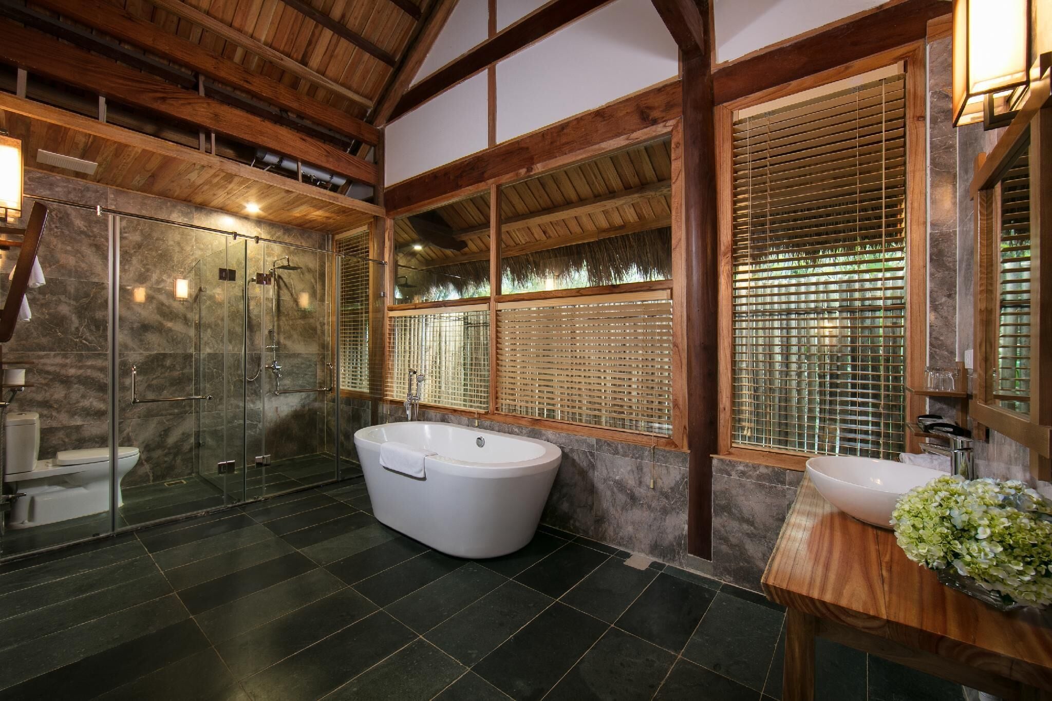 A modern bathroom with a freestanding bathtub, a glass-enclosed shower, and a wooden vanity with a sink.