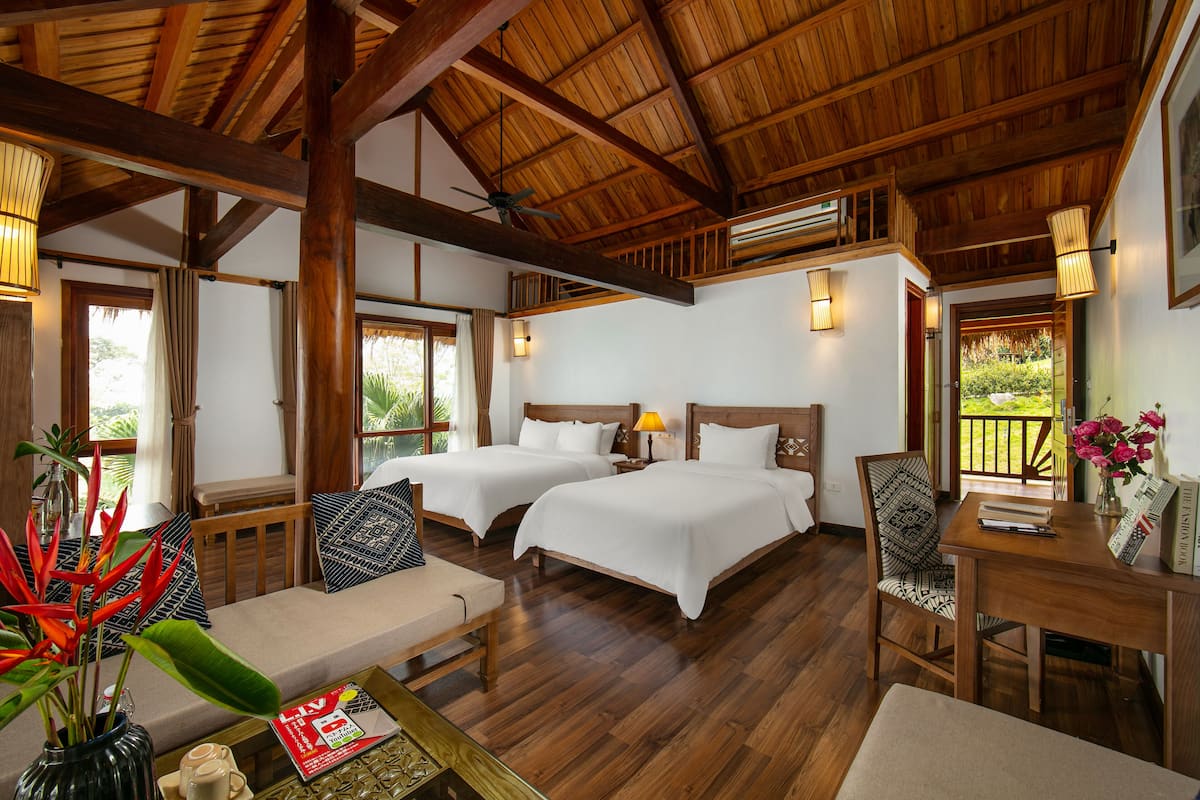 Une chambre d’hôtel avec deux lits, un plafond en bois et un balcon avec vue.