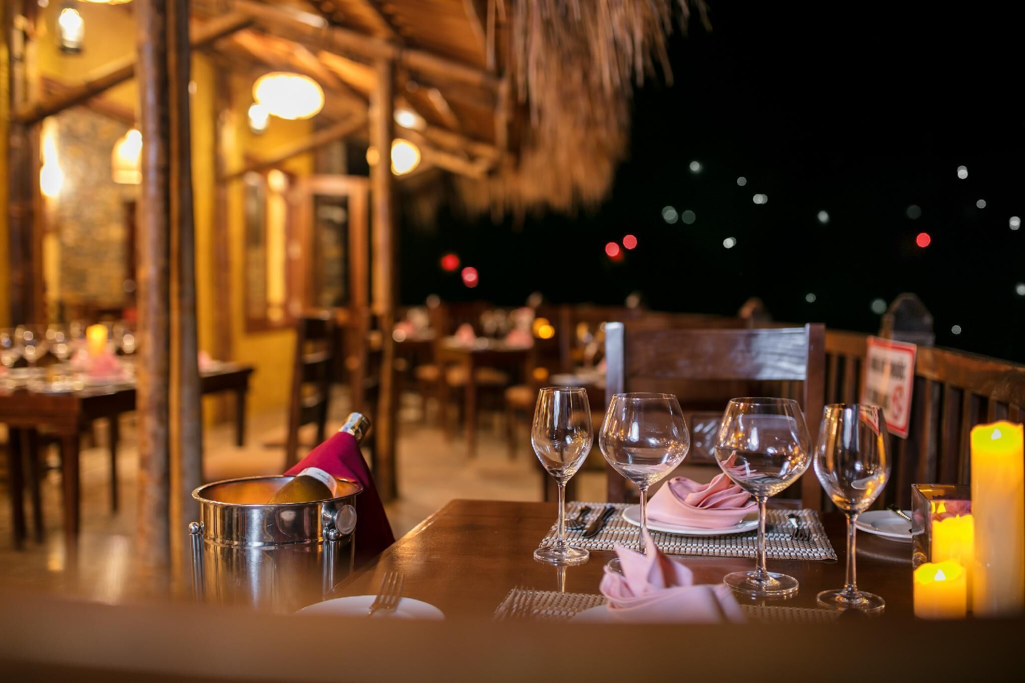 A dining table set with wine glasses, a candle, and a menu stand.