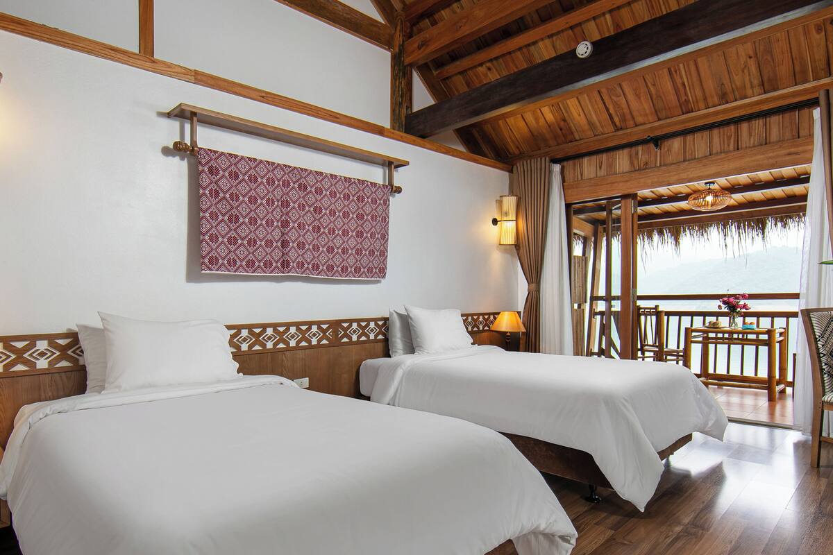 Une chambre d’hôtel avec deux lits, un plancher en bois, une décoration murale à motifs et un balcon avec vue.