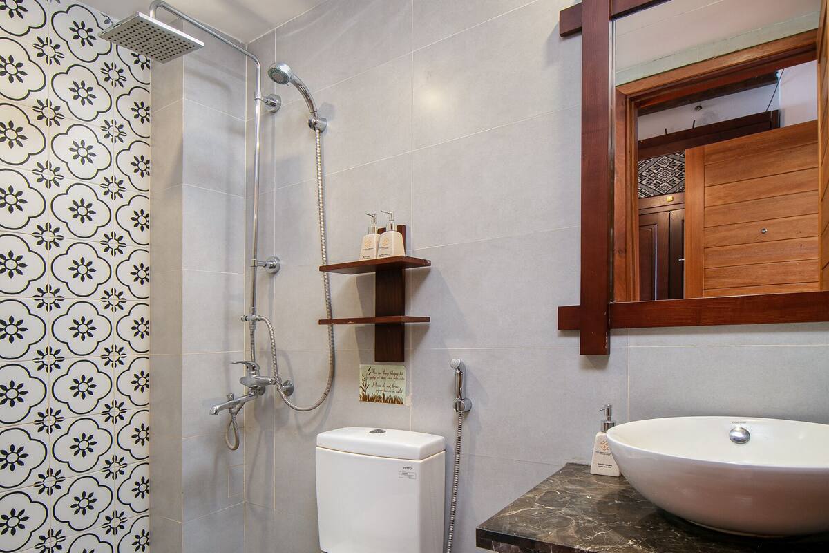 Une salle de bain équipée de toilettes, d’une douche, d’un lavabo et d’un miroir.
