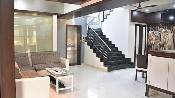A modern living room with a sofa, coffee table, and a staircase leading to an upper floor. - Hotel South Coast (Navi Mumbai)