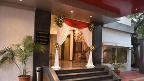 A hotel entrance with a red curtain, white drapes, and floral decorations. - Hotel South Coast (Navi Mumbai)
