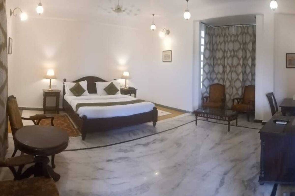 Ein Hotelzimmer mit einem Bett, einem Schreibtisch, zwei Stühlen, einem kleinen Tisch und einem Fernseher.