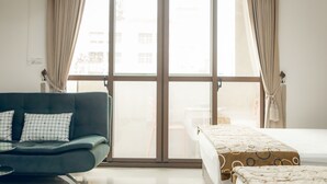 A room with a sofa, a bed, and a large window with curtains. - Goodfriend B&B (Magong)