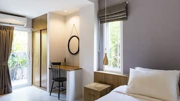 A bedroom with a bed, a desk, a chair, and a window with curtains.