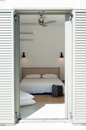 Quarto com cama, almofadas, ventilador de teto e duas luminárias.