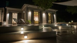 Una casa moderna con piscina, mobiliario exterior e iluminacion en las entradas.