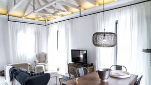 Una sala de estar moderna con un sofá, sillas, una mesa de comedor, un televisor y una lámpara colgante.