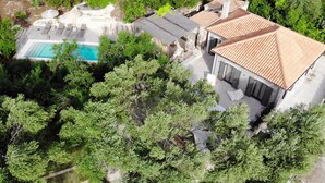 Vista aérea de una propiedad con piscina, sillas de descanso y un edificio con techo de tejas.