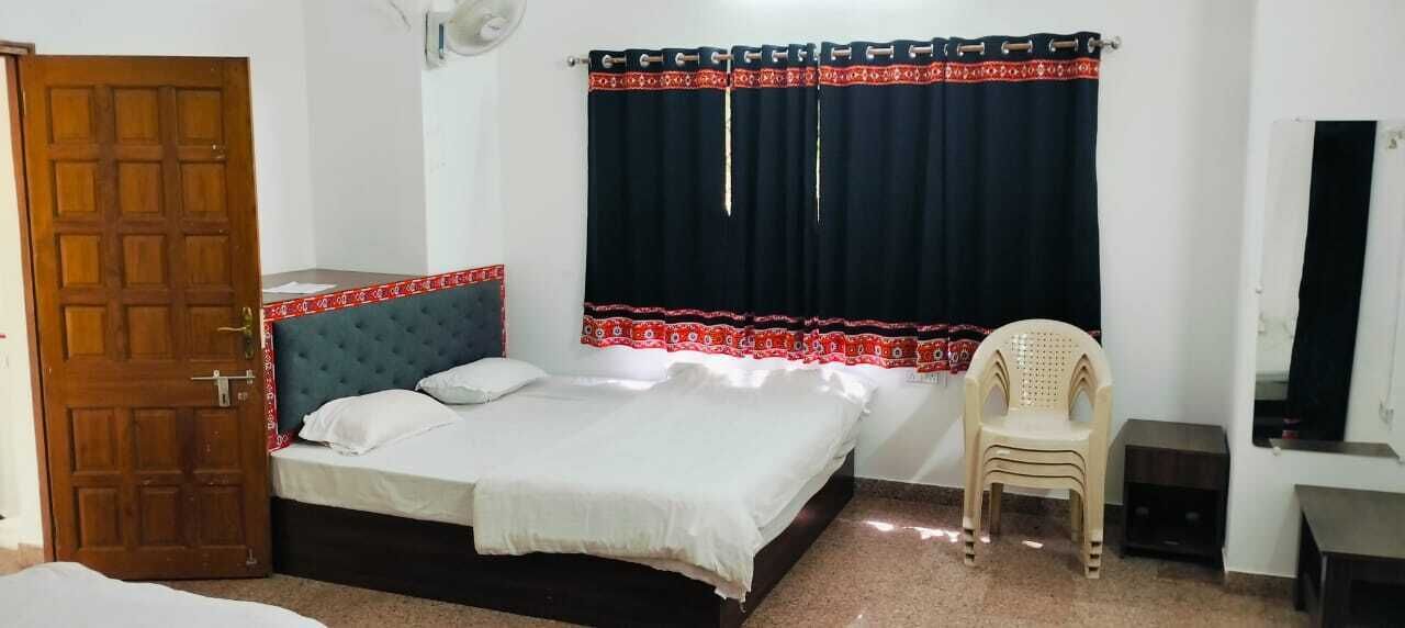 A bedroom with a bed, a chair, a desk, a wardrobe, and a door.