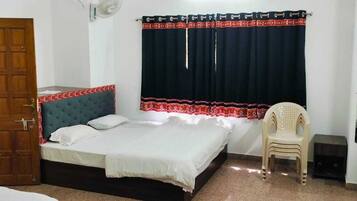 A bedroom with a bed, a chair, a desk, a wardrobe, and a door.