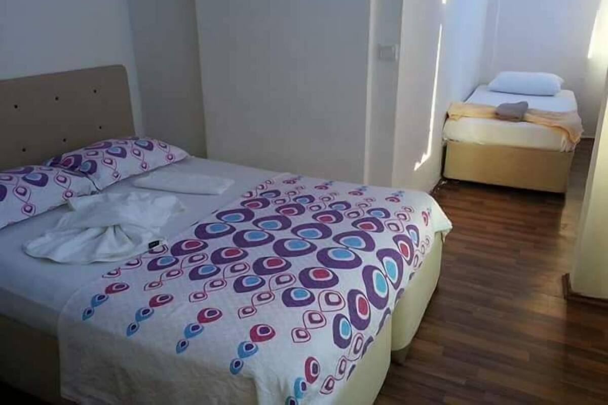 Une chambre à coucher avec un lit recouvert d’une couvre-lit à motifs, une table de chevet et une petite lampe de chevet.